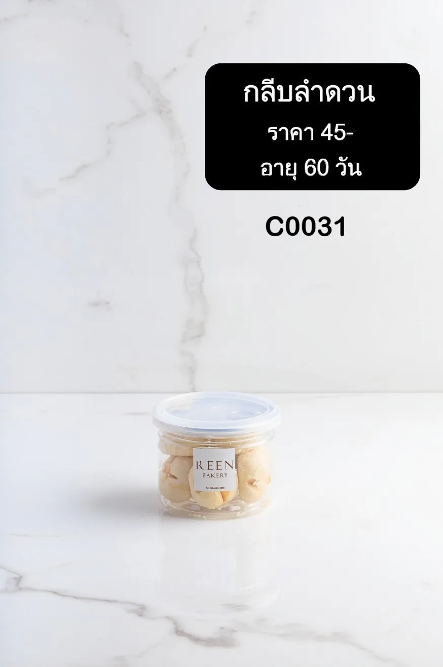 คุกกี้กลีบลำดวนสีขาวนวลบรรจุในกระปุกพลาสติกใส มีฉลาก REEN BAKERY วางอยู่บนพื้นผิวหินอ่อนสีขาว
