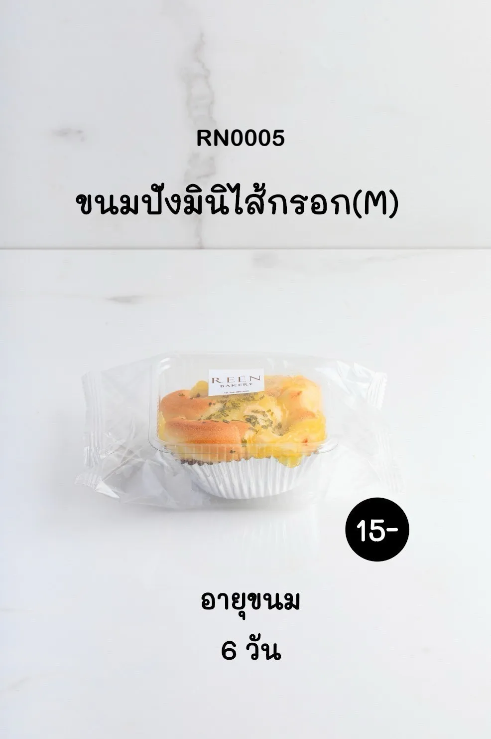 ขนมปังมินิไส้กรอกขนาด M หนึ่งชิ้นในถ้วยฟอยล์สีเงิน บรรจุในกล่องพลาสติกใสพร้อมโลโก้ REEN BAKERY และห่อด้วยถุงพลาสติกใส วางอยู่บนพื้นผิวสีขาว
