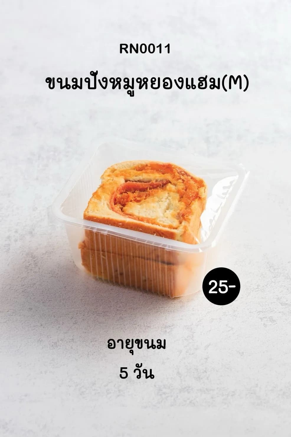 ขนมปังหมูหยองแฮมขนาดกลาง (M) หนึ่งชิ้นบรรจุในกล่องพลาสติกใส วางอยู่บนพื้นผิวสีขาวเทาอ่อน