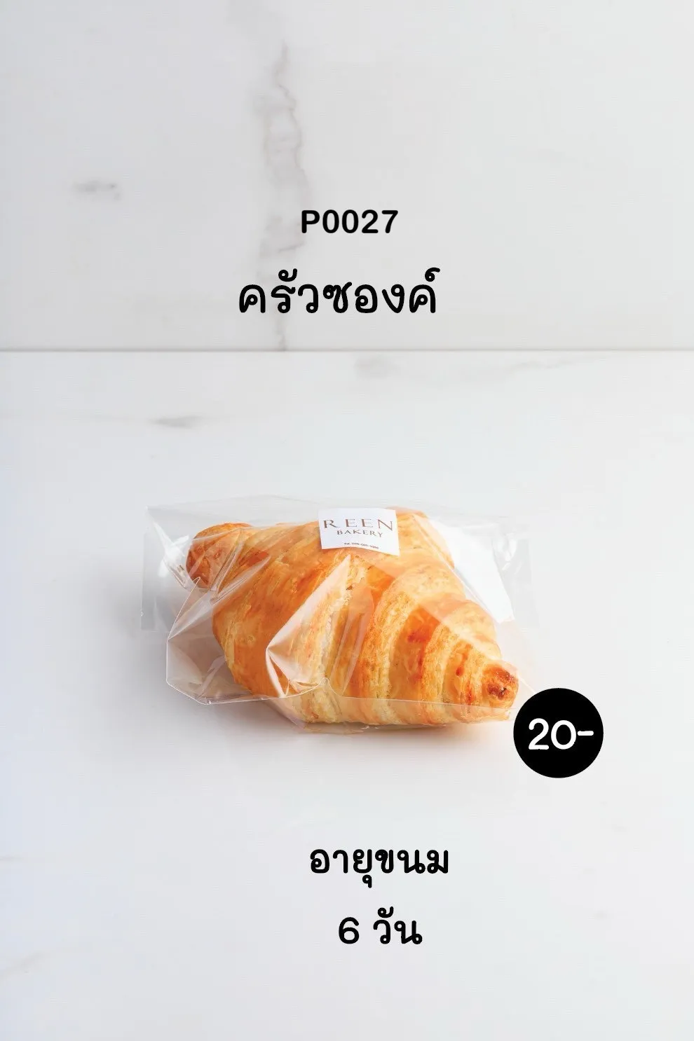 ครัวซองต์สีทองเหลืองอร่ามบรรจุในซองพลาสติกใสมีฉลาก REEN BAKERY วางอยู่บนพื้นหินอ่อนสีขาว