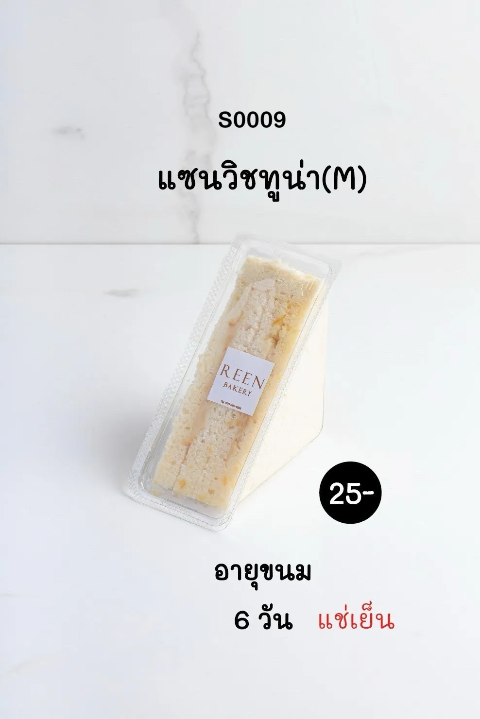 แซนวิชทูน่าขนาดกลาง (M) หนึ่งชิ้น บรรจุในกล่องพลาสติกใสทรงสามเหลี่ยม วางอยู่บนพื้นผิวสีขาวสะอาด ด้านหน้ากล่องมีฉลาก REEN BAKERY
