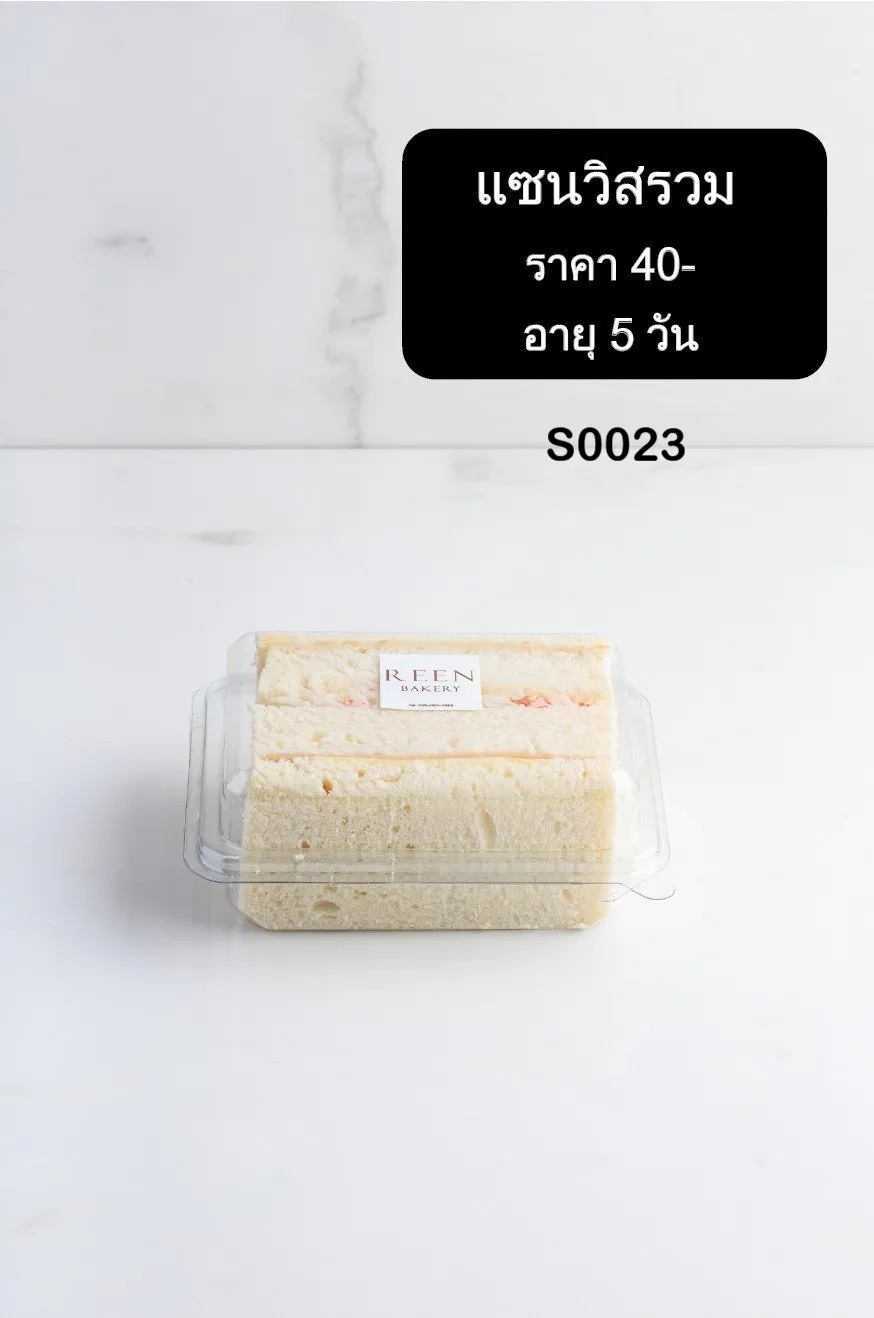 แซนวิชรวมสองชิ้นวางในกล่องพลาสติกใส แซนวิชทำจากขนมปังขาวนุ่ม ตัดแนวทแยง มีไส้ผสมอยู่ภายใน และมีฉลาก REEN BAKERY ติดอยู่บนกล่อง