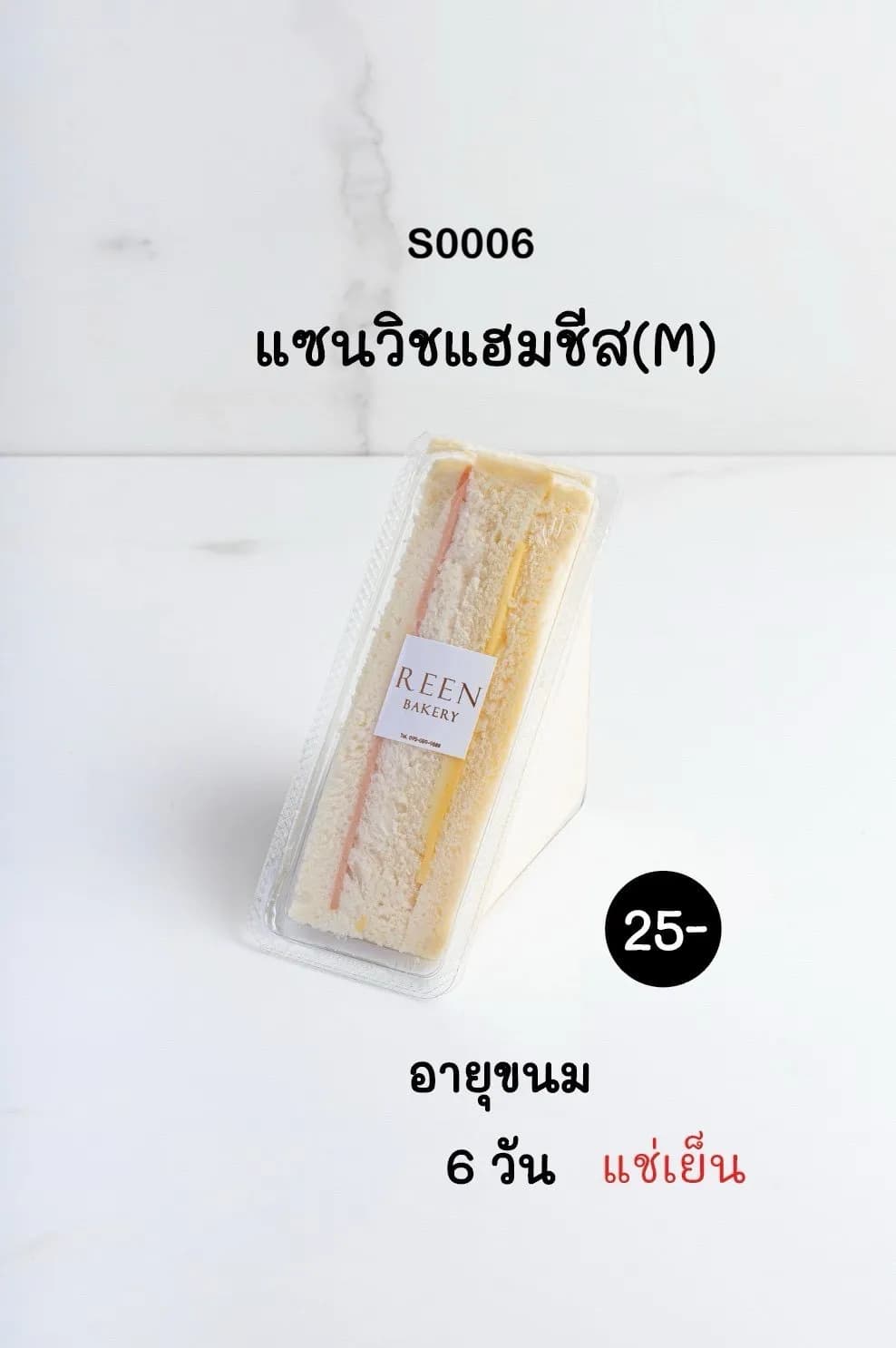 แซนวิชแฮมชีสขนาด M บรรจุในกล่องพลาสติกใส รูปทรงสามเหลี่ยม เห็นเนื้อขนมปังขาว ไส้แฮมสีชมพู และชีสสีเหลือง มีฉลาก REEN BAKERY ติดอยู่