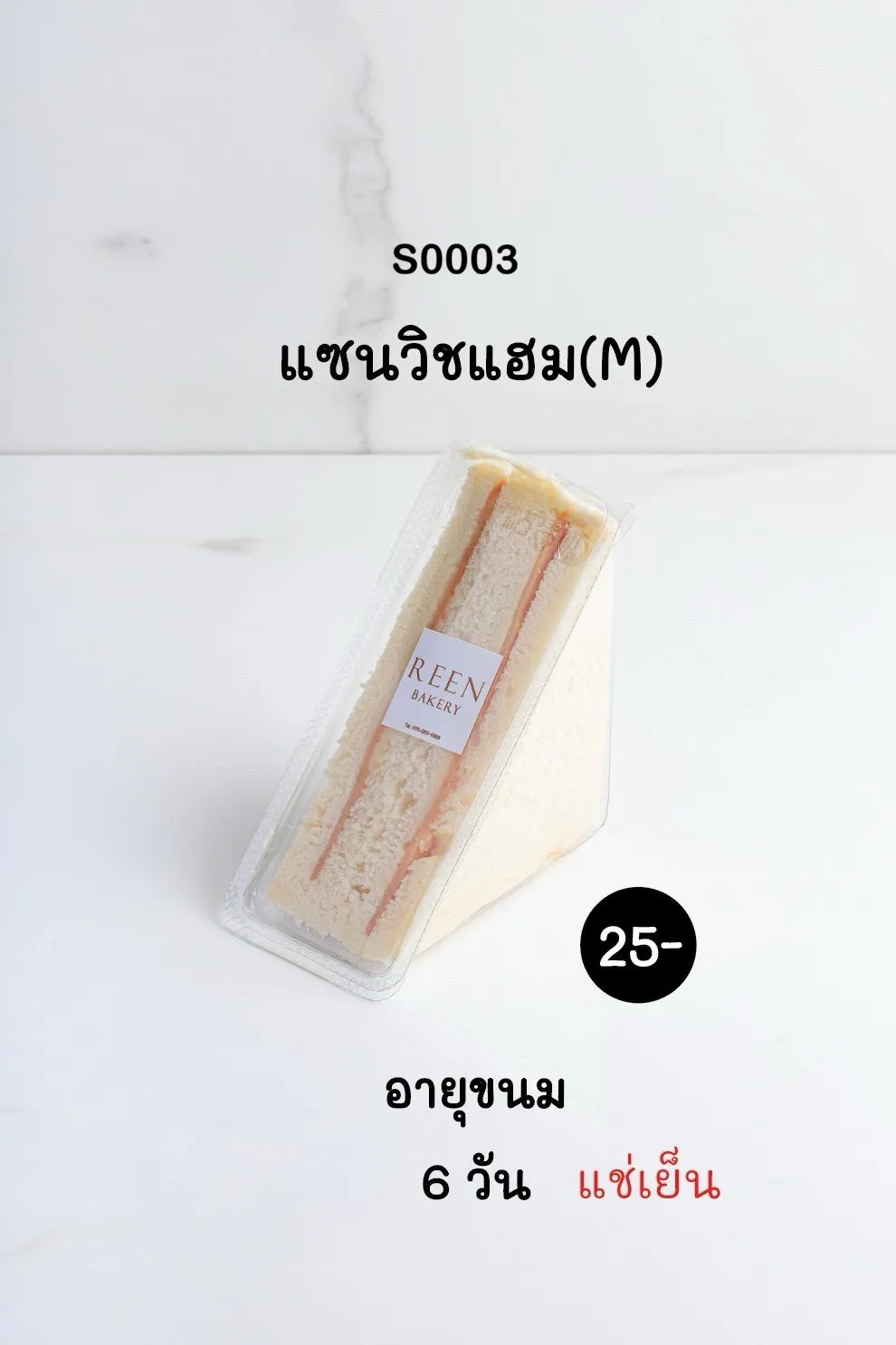ภาพแซนวิชแฮมขนาดกลาง (M) ในบรรจุภัณฑ์พลาสติกใสทรงสามเหลี่ยม พร้อมฉลาก REEN BAKERY วางอยู่บนพื้นผิวสีขาว แสดงให้เห็นเนื้อขนมปังขาวและไส้แฮม